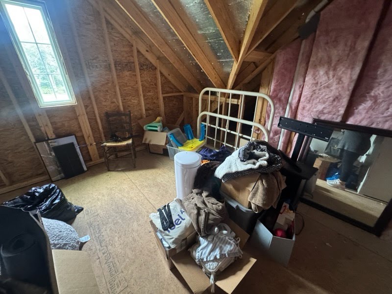 Attic before cleanout with furniture, boxes, and loose items